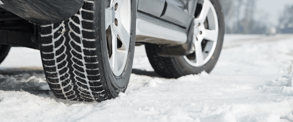 Car equipped with snow tires parked on a snowy road, ready for winter driving.