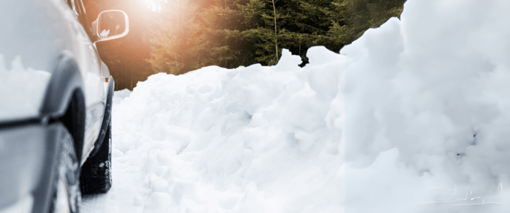 A car skillfully navigates the snowy road, gracefully handling the challenges of winter driving. Surrounded by towering snowbanks and majestic trees, it glides under the gentle warmth of sunlight, embodying resilience amidst serene wintry beauty.