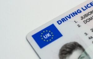 Close-up of a corner of a UK driving license with a blue and yellow EU symbol and part of a person's photo visible.