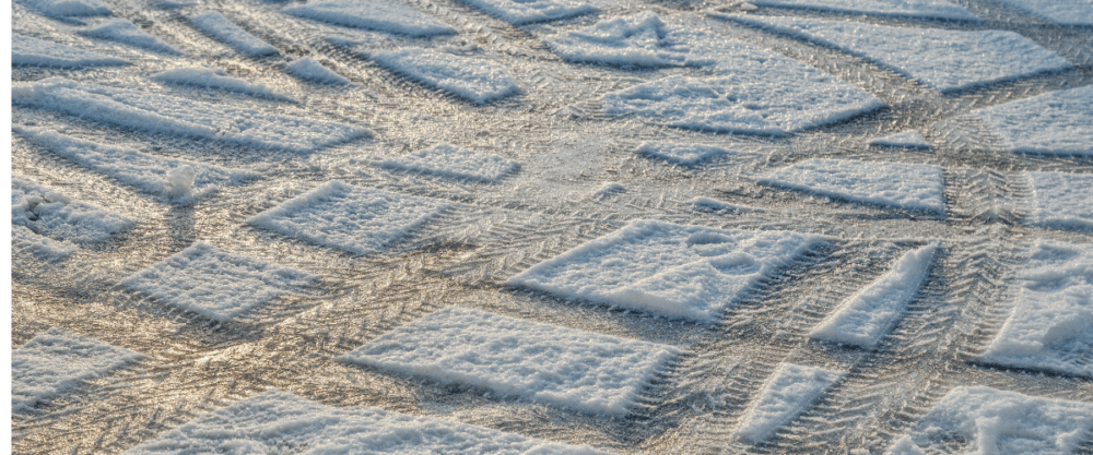 The snow-covered ground showcases various geometric patterns, while tire tracks reveal the art of winter driving etched on the surface.