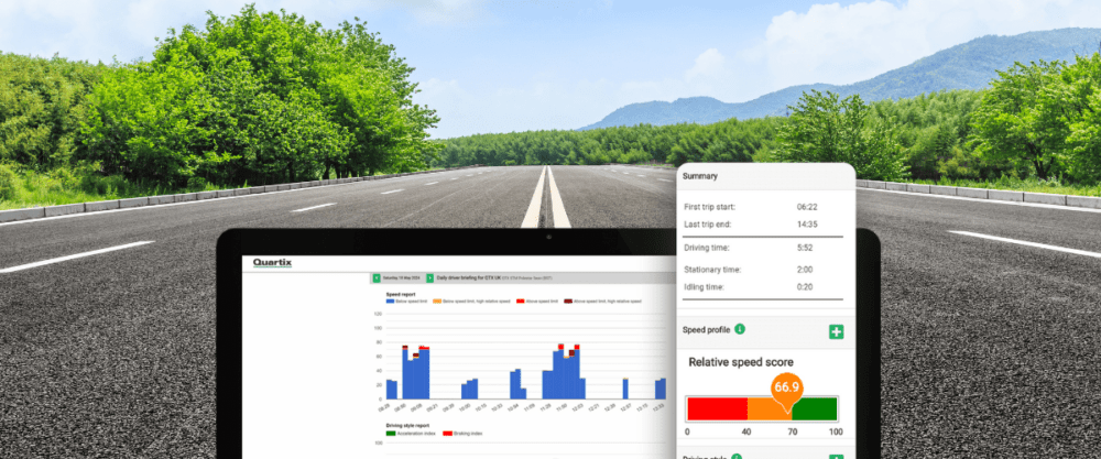 Laptop on an open road displaying driving analytics graphs and statistics on the screen, set against a backdrop of green trees and mountains under a blue sky.